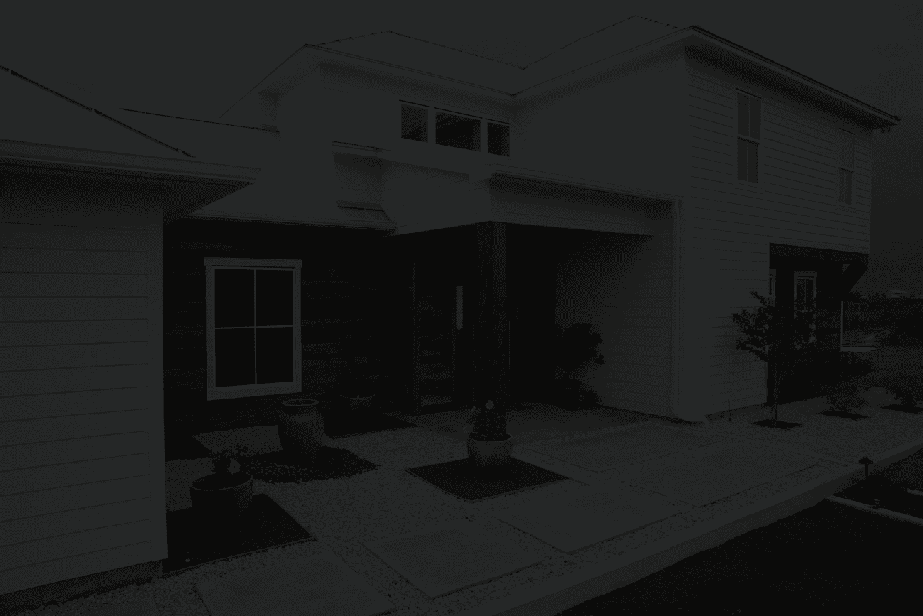 Modern white house with metal roof, wooden accents, and large windows. The landscaped front yard has potted plants and gravel paths, exuding a clean, minimalist vibe.